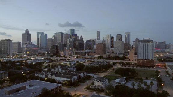 Downtown city skyline at dusk with high-rise buildings and residential homes in the foreground