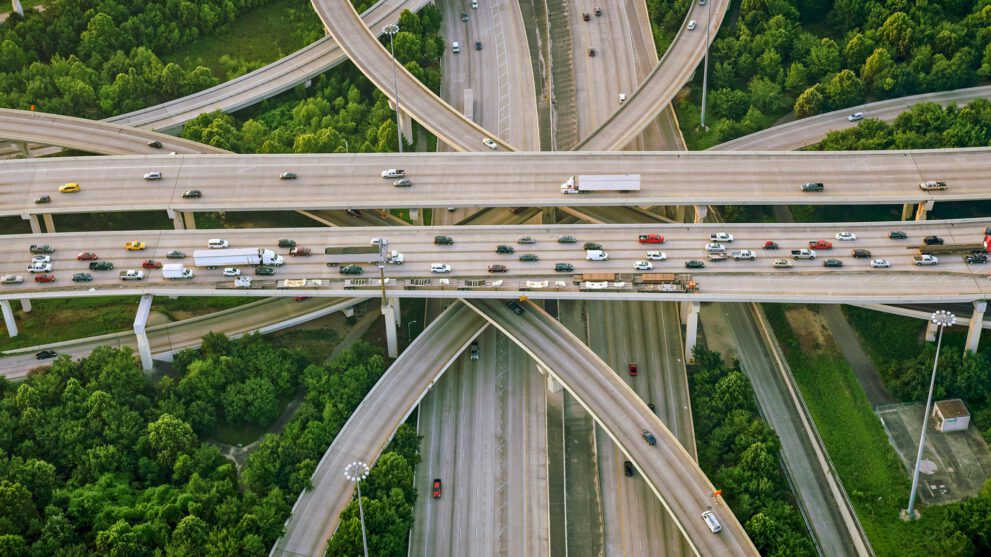 Aerial view of busy multi-level highway interchange surrounded by trees